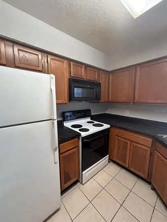 a kitchen with granite countertop a refrigerator and a stove top oven