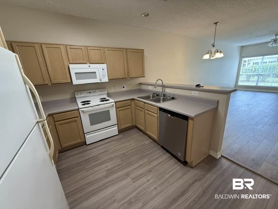 2651 South Juniper Street, Unit 401 Foley, AL 36535 - Photo 13 of 27 Kitchen featuring a sink, light brown cabinetry, a peninsula, light wood-style flooring, and white appliances