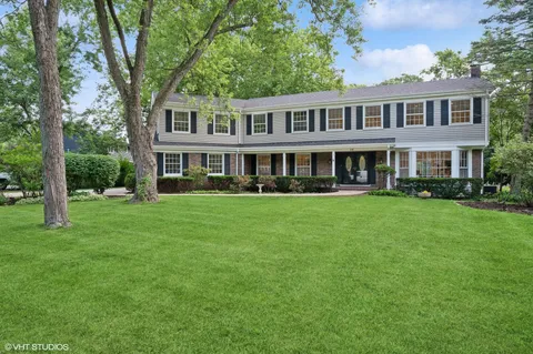 a front view of a house with garden and trees