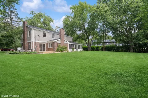 a view of a house with a big yard and large trees