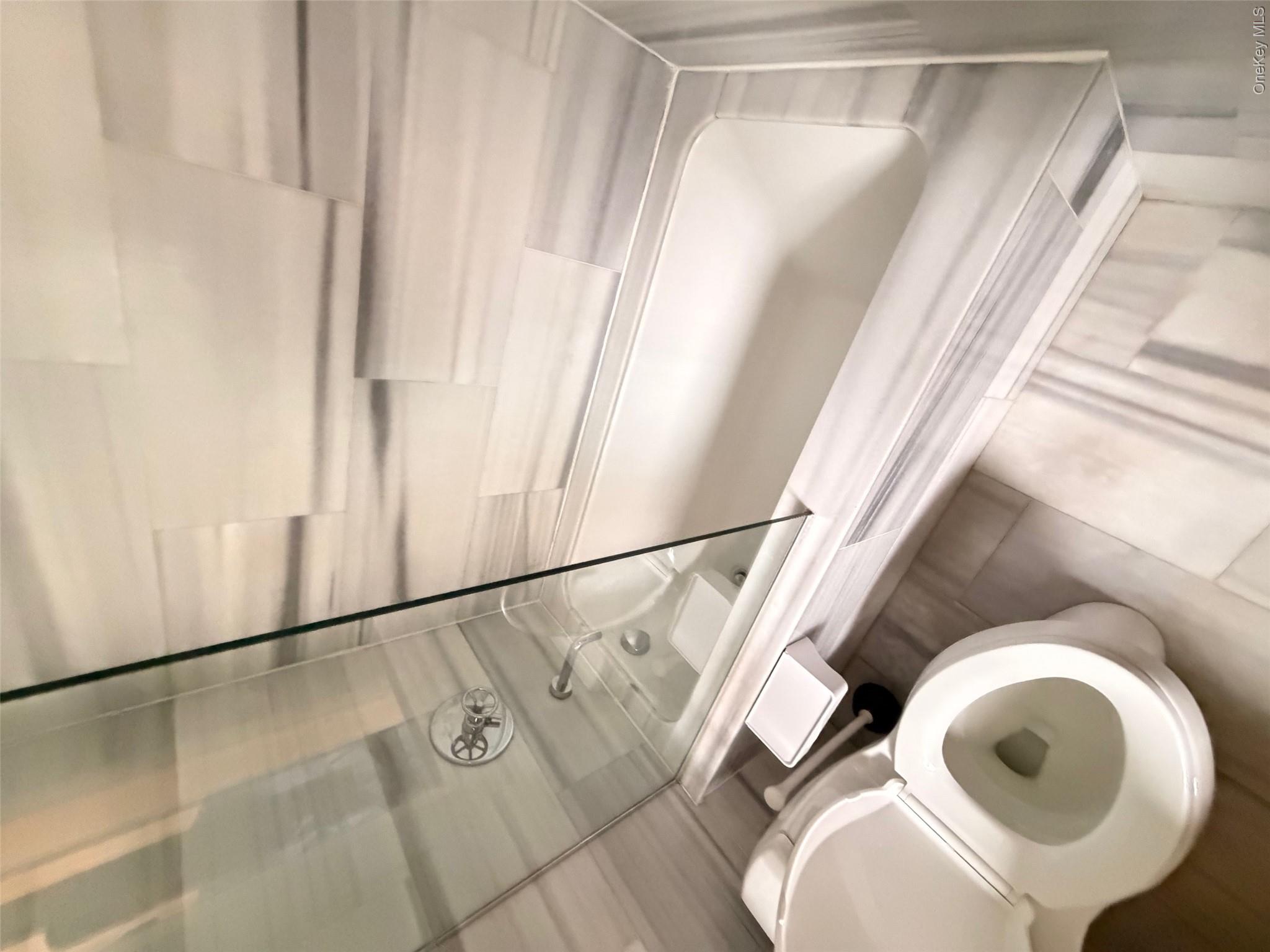 225 Rector Place, Unit 7E Manhattan, NY 10280 - Photo 12 of 19 Bathroom featuring a white soaking tub with a glass shower enclosure and tiled surround