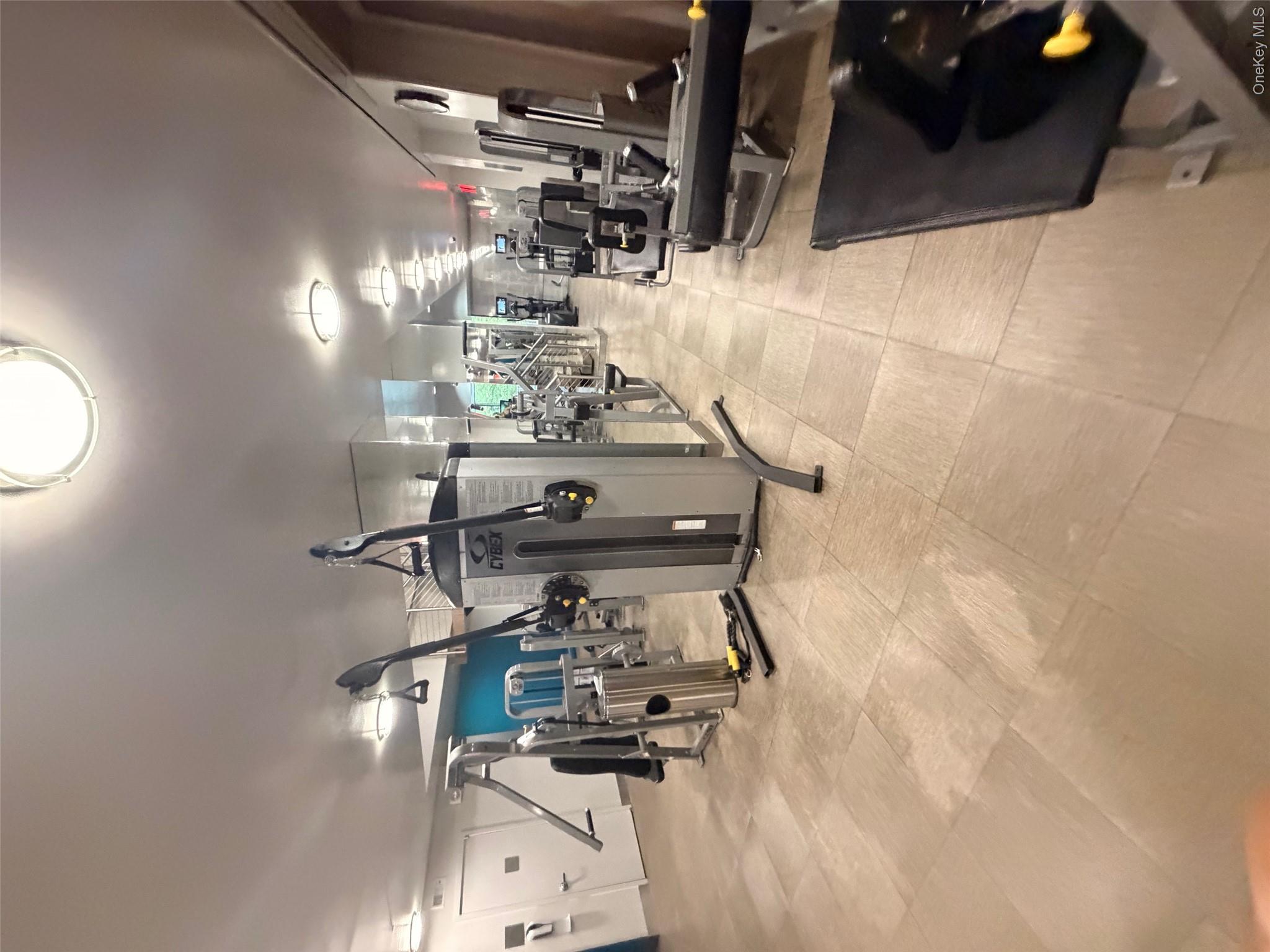 225 Rector Place, Unit 7E Manhattan, NY 10280 - Photo 16 of 19 Fitness center featuring extensive exercise equipment, tile flooring, mirrored walls, and recessed lighting