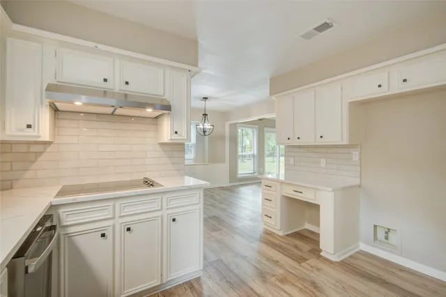 a kitchen with stainless steel appliances white cabinets and wooden floors