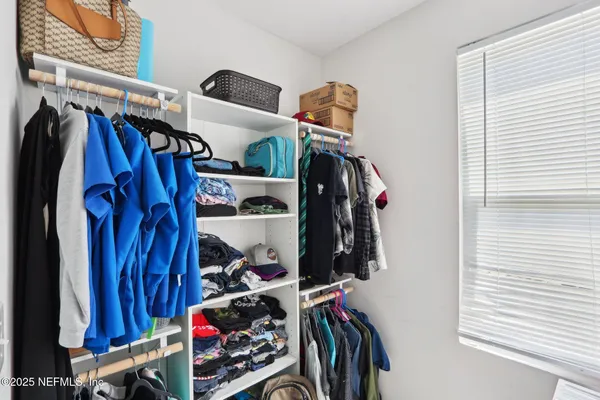a view of walk in closet with clothes and shoes