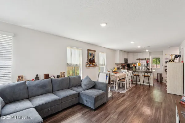 a living room with furniture kitchen view and a wooden floor