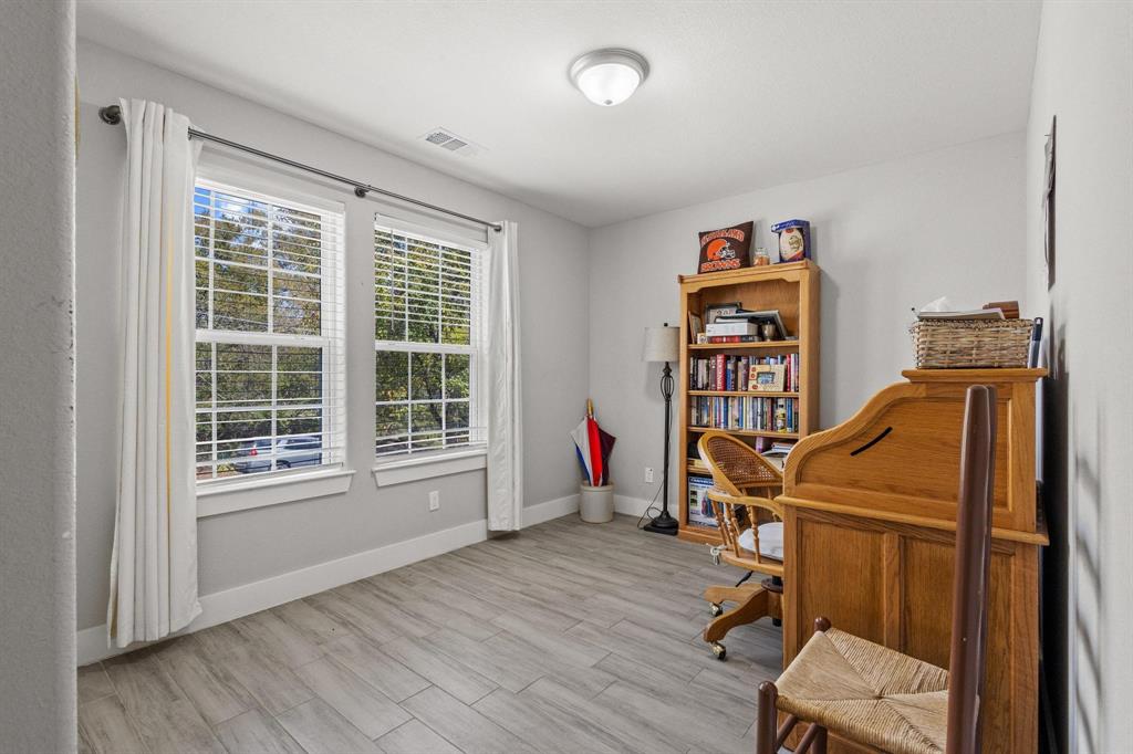 608 East Shepherd Street Denison, TX 75021 - Photo 22 of 31 Spacious room featuring two large windows, wood-finish flooring, light gray wall paint, white baseboards, and a flush-mount ceiling light fixture