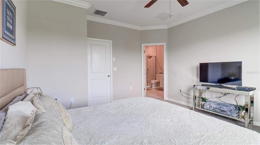 31632 Blue Passing Loop Wesley Chapel, FL 33545 - Photo 28 of 48 a bedroom with a bed and a flat tv screen on a dresser