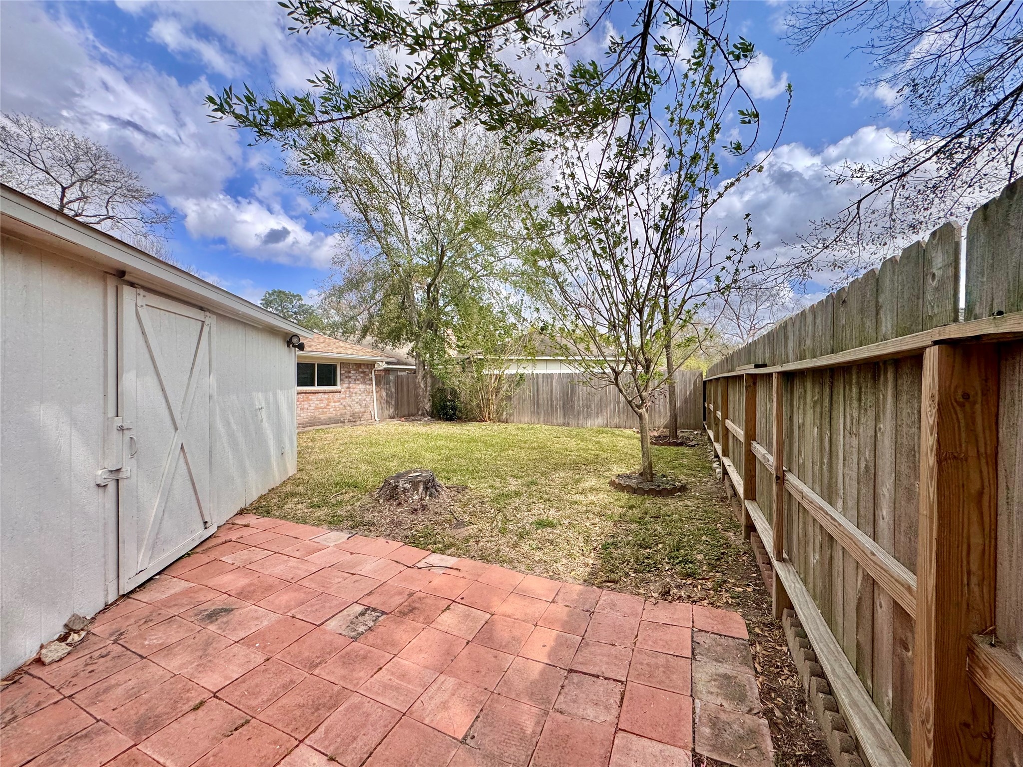 9719 Springmont Drive Houston, TX 77080 - Photo 32 of 32 Tucked away behind the garage is more usable paved yard space … perfect for a separate function like raised garden beds or just another cute sitting area! Behind a sliding barn door is a wonderful large storage shed attached to the back of the garage structure! What a plus for a gardener or home DIYer!!