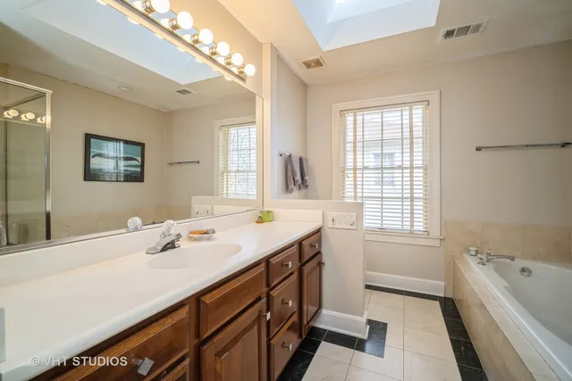 a bathroom with a tub a sink and a large mirror