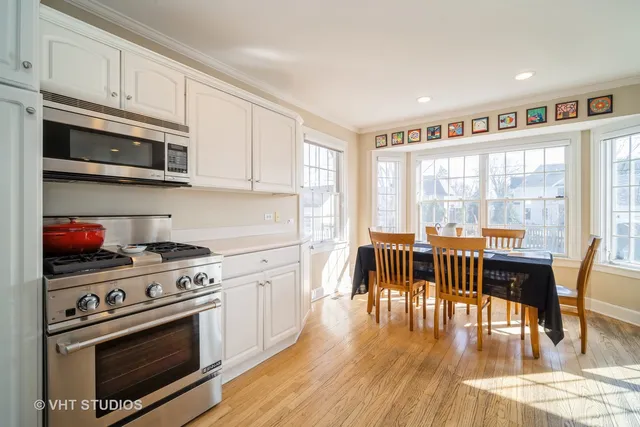 a kitchen with stainless steel appliances a stove a dining table and chairs with wooden floor