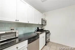 a kitchen with granite countertop white cabinets and black appliances