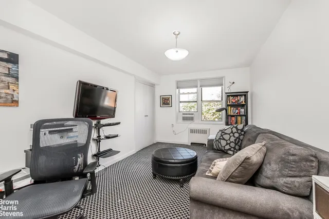 a living room with furniture a flat screen tv and a window