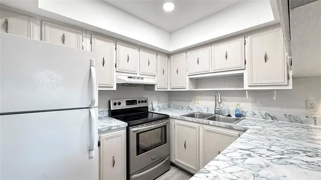 a kitchen with stainless steel appliances granite countertop white cabinets sink and a refrigerator
