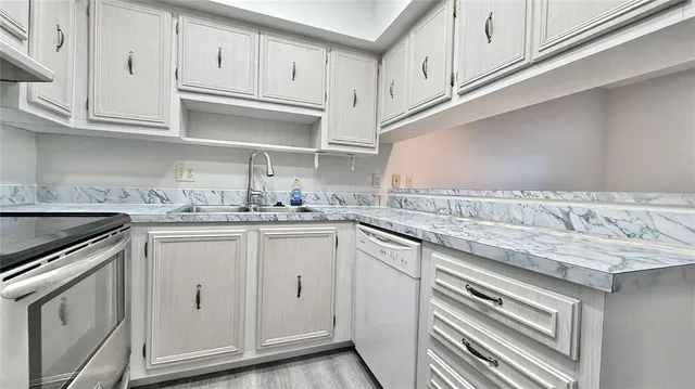 a kitchen with granite countertop white cabinets and white appliances