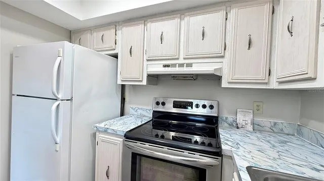 a kitchen with stainless steel appliances granite countertop a refrigerator stove and white cabinets