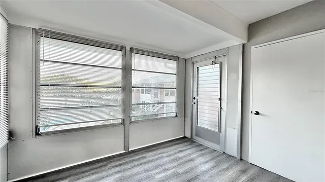 a view of an empty room with a window and wooden floor