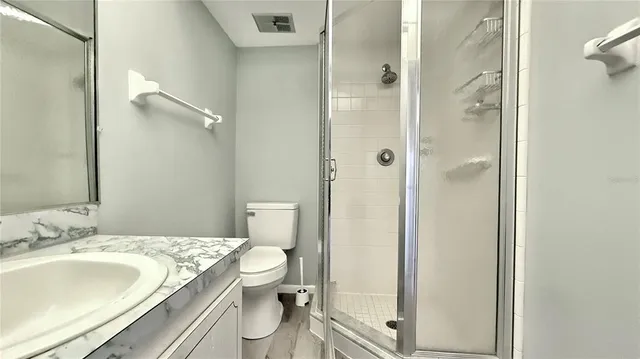 a bathroom with a granite countertop sink toilet and shower