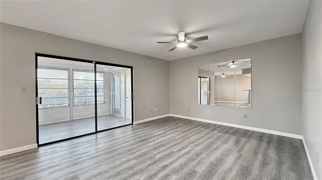 an empty room with wooden floor fan and windows
