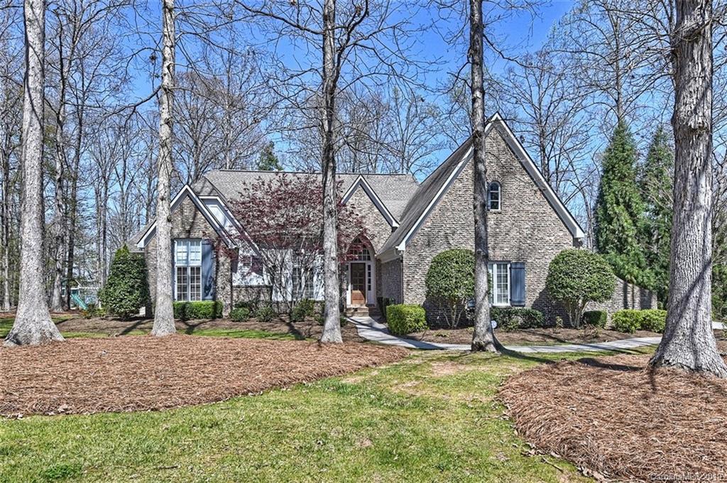 a view of a house with a yard and large trees