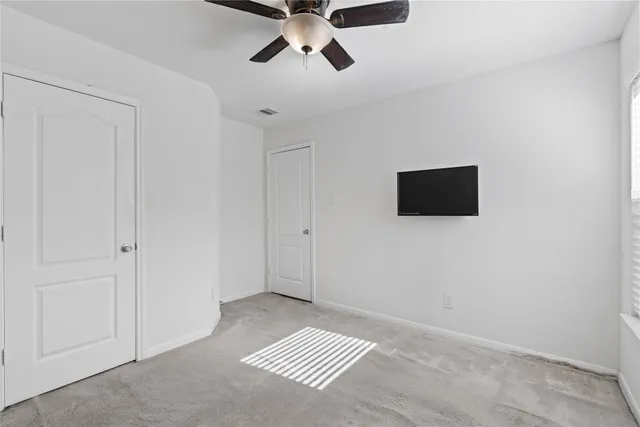 a view of an empty room and chandelier fan