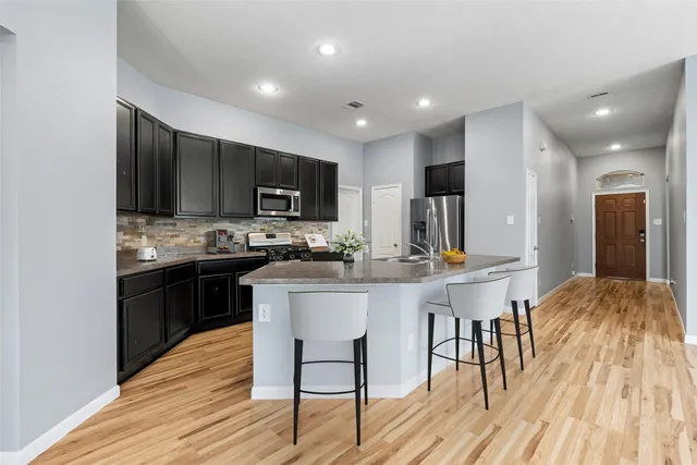 a kitchen with stainless steel appliances kitchen island granite countertop a sink cabinets and wooden floor