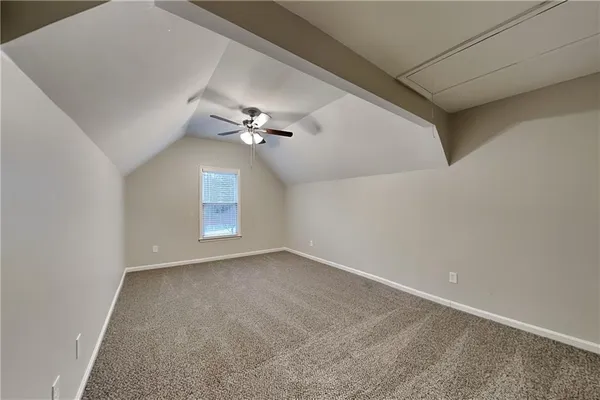 an empty room with a chandelier fan and windows