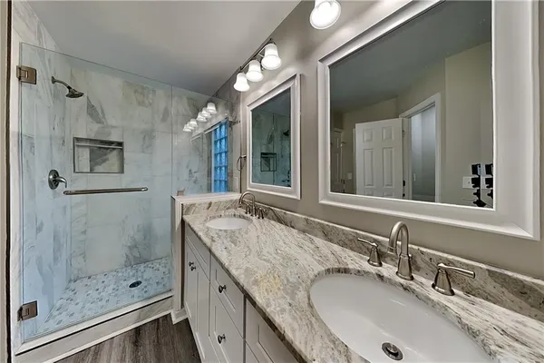 a bathroom with a granite countertop double vanity sink mirror and shower