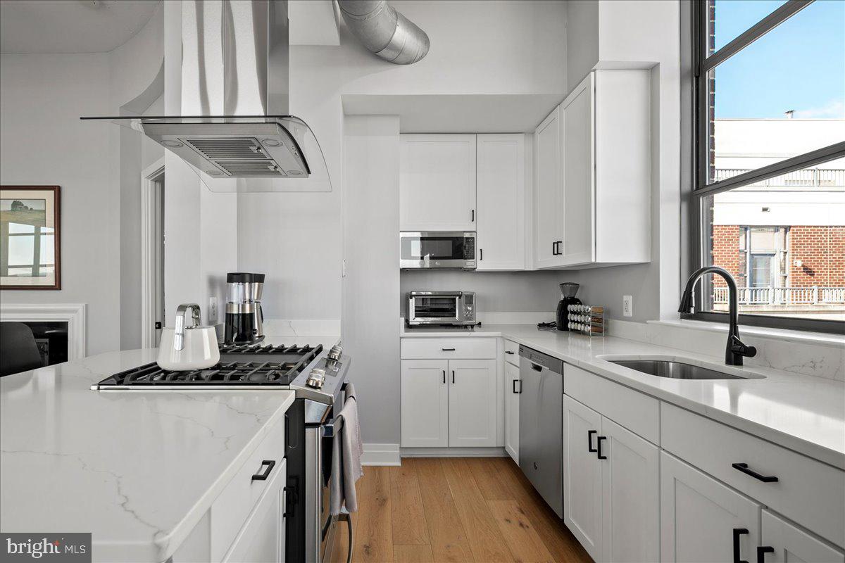 2020 12th Street Northwest, Unit 812 Washington, DC 20009 - Photo 12 of 38 a kitchen with stainless steel appliances a sink dishwasher stove and white cabinets with wooden floor