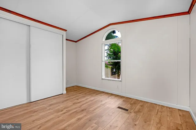 a view of an empty room with a window and hardwood floor