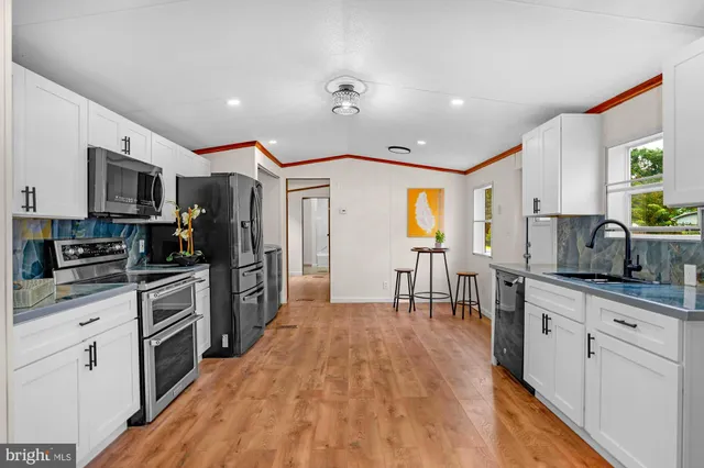 a kitchen with stainless steel appliances kitchen island granite countertop a stove top oven a sink a dining table and chairs with wooden floor
