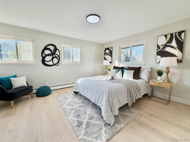 a bedroom with a bed a painting on the wall and a potted plant