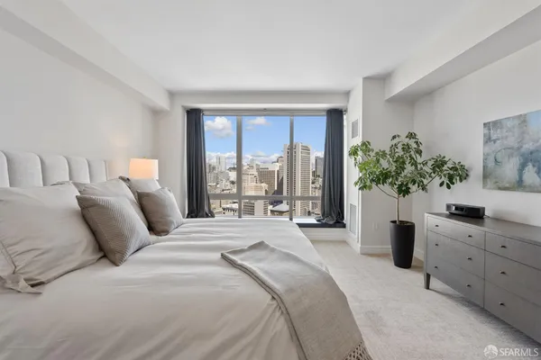 a large bed sitting in a bedroom next to a lamp and a large window