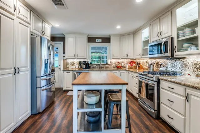 a kitchen with stainless steel appliances granite countertop a refrigerator and a stove top oven
