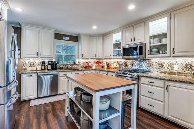 a kitchen with stainless steel appliances a stove a sink and a refrigerator with wooden floor