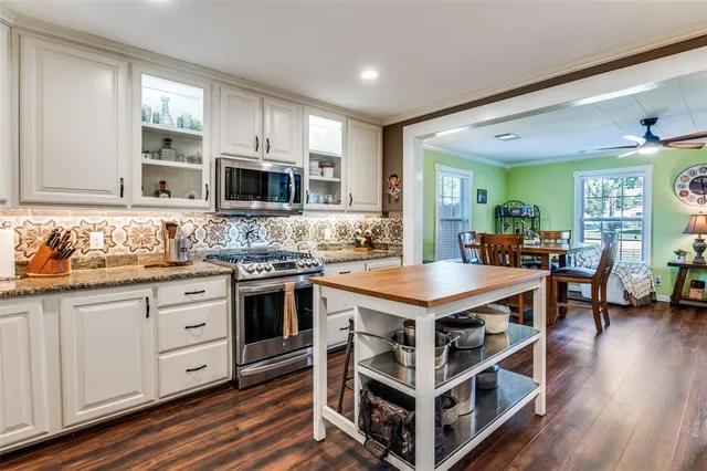 a dining room with wooden floor a chandelier fan a wooden table and chairs