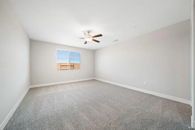 an empty room with a window and a ceiling fan