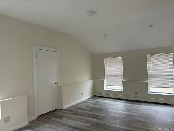 a view of an empty room with wooden floor and windows