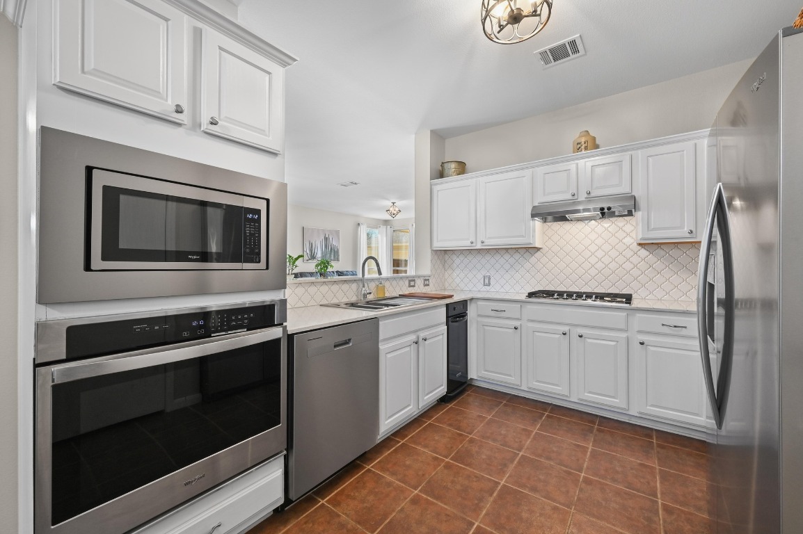 400 Tobin Drive Buda, TX 78610 - Photo 15 of 40 Kitchen featuring stainless steel appliances, white cabinetry, light countertops, backsplash, and dark tile patterned floors