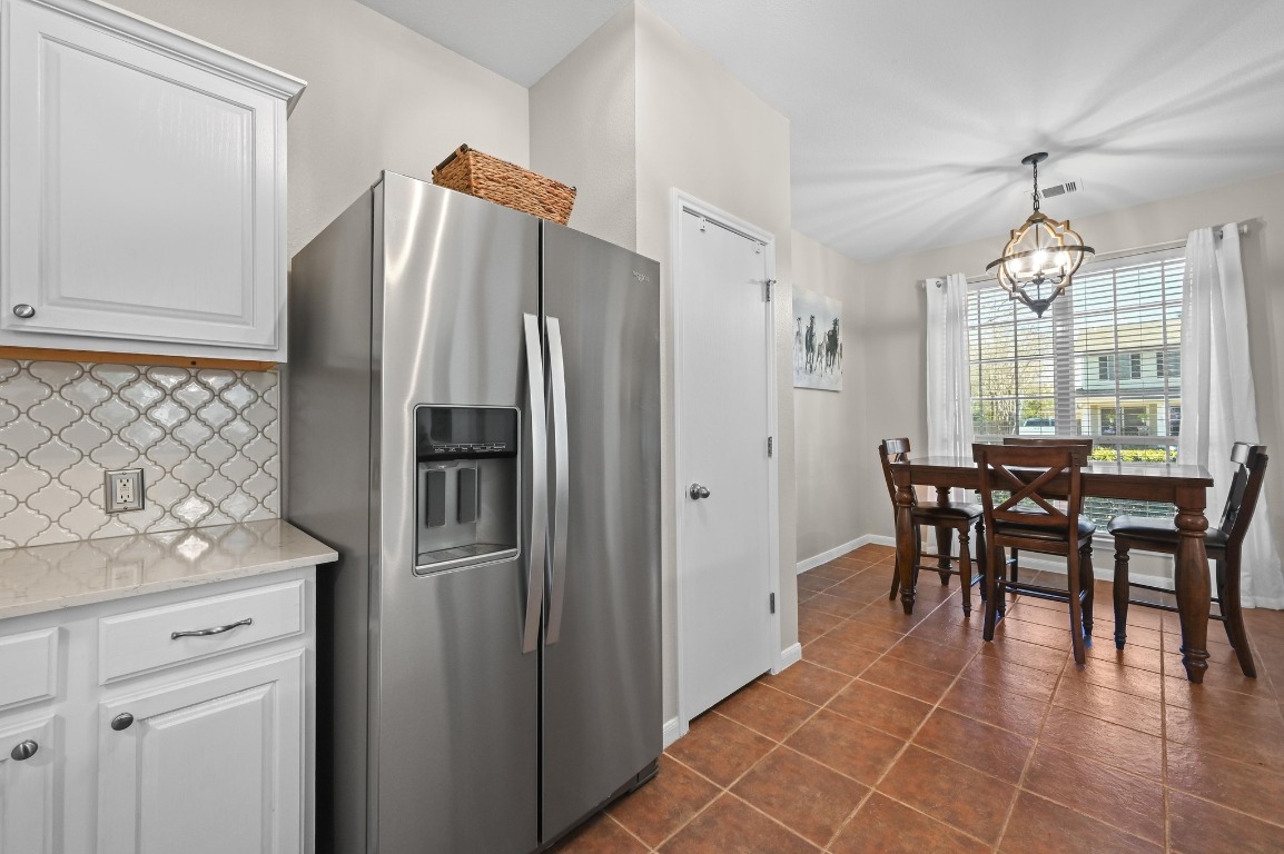 400 Tobin Drive Buda, TX 78610 - Photo 16 of 40 Kitchen with stainless steel fridge with ice dispenser, white cabinets, pantry, light stone countertops, and decorative backsplash