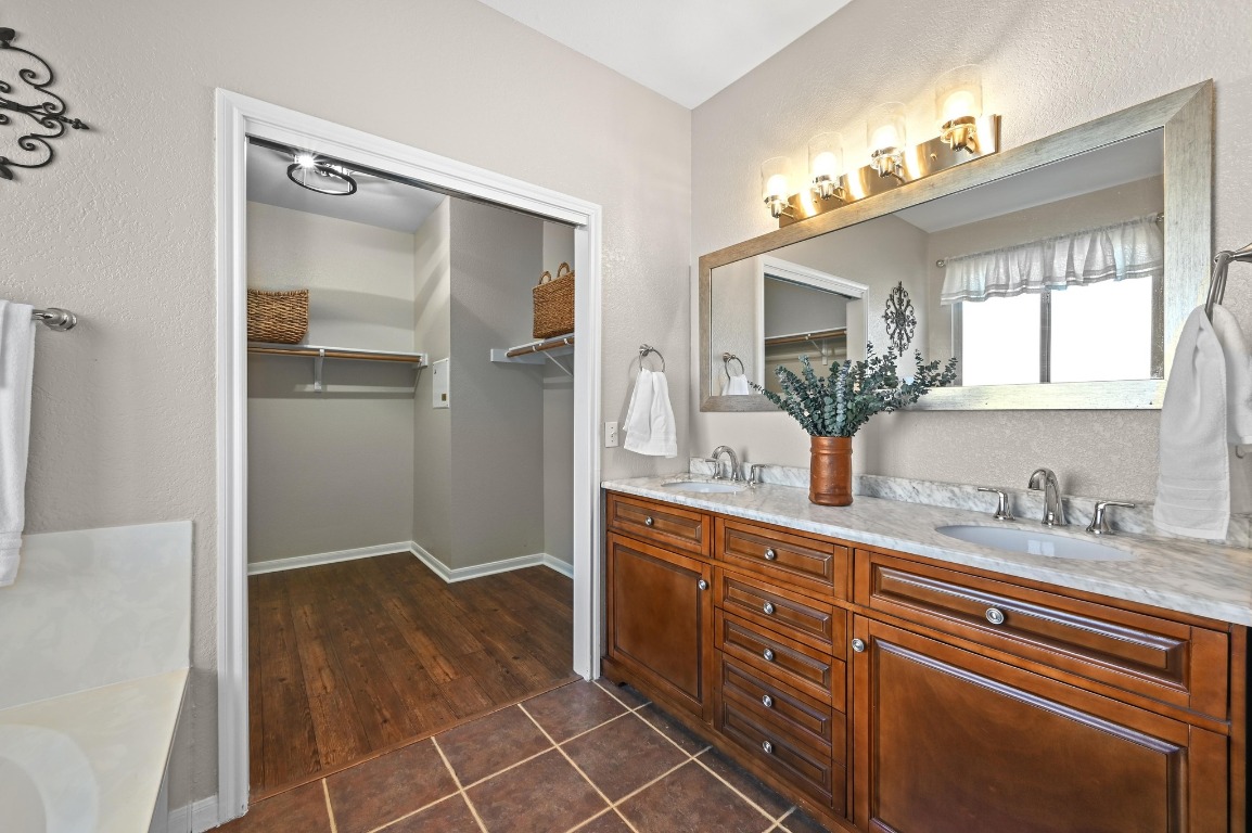 400 Tobin Drive Buda, TX 78610 - Photo 20 of 40 Full bath featuring a spacious closet, double vanity, a bathtub, dark tile patterned flooring, and a textured wall