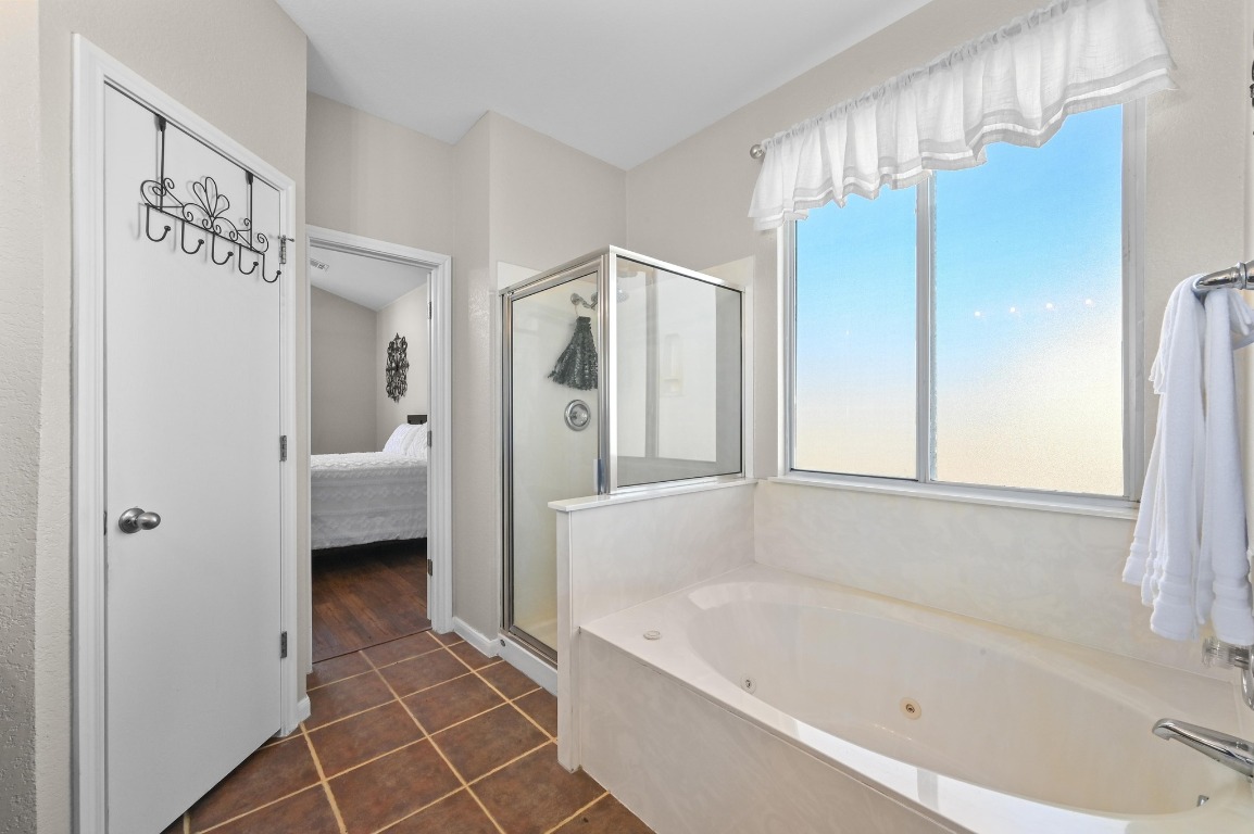 400 Tobin Drive Buda, TX 78610 - Photo 21 of 40 Ensuite bathroom with a shower stall, dark tile patterned floors, and a tub with jets