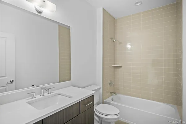 a bathroom with a bathtub shower sink vanity mirror and toilet