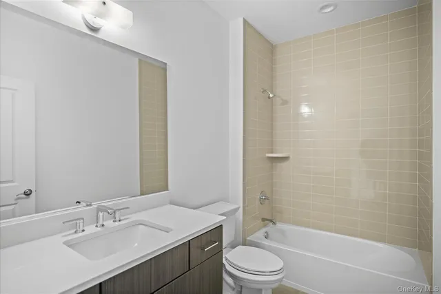 a bathroom with a bathtub shower sink vanity mirror and toilet