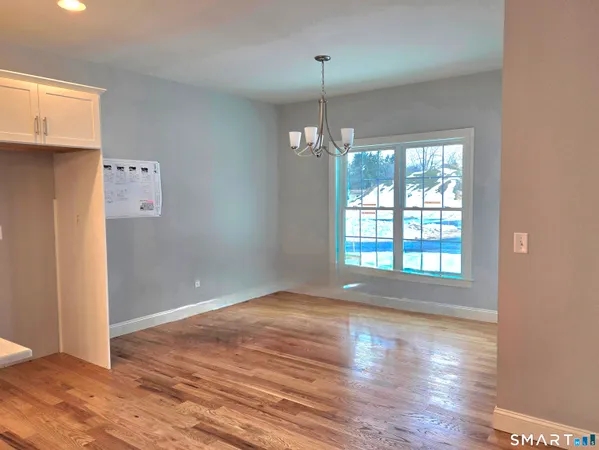 a view of an empty room with wooden floor and windows
