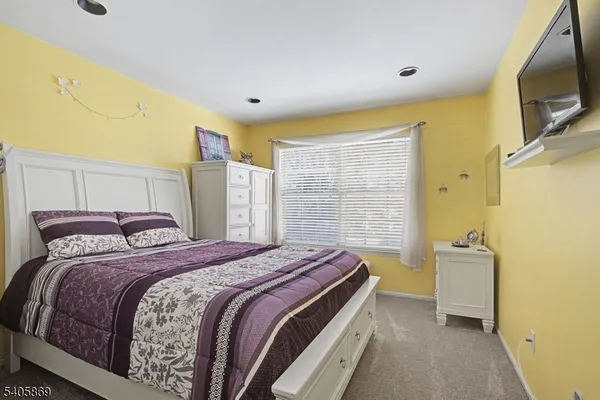 a bedroom with a bed and a flat tv screen on dresser