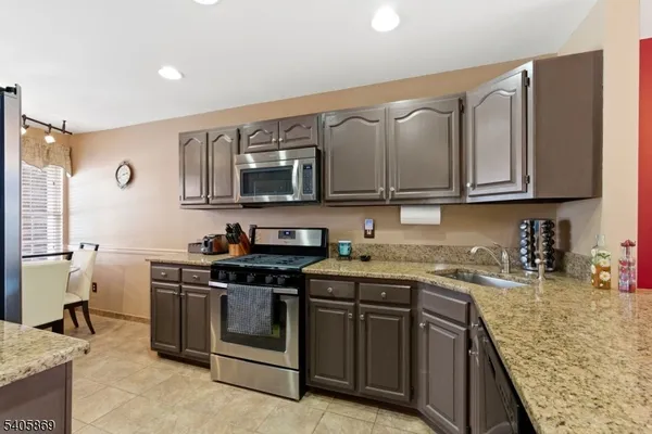 a kitchen with stainless steel appliances granite countertop a stove top oven a sink dishwasher and a microwave oven with white cabinets