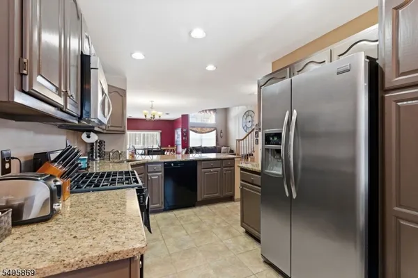 a kitchen with stainless steel appliances granite countertop a refrigerator a stove and a sink