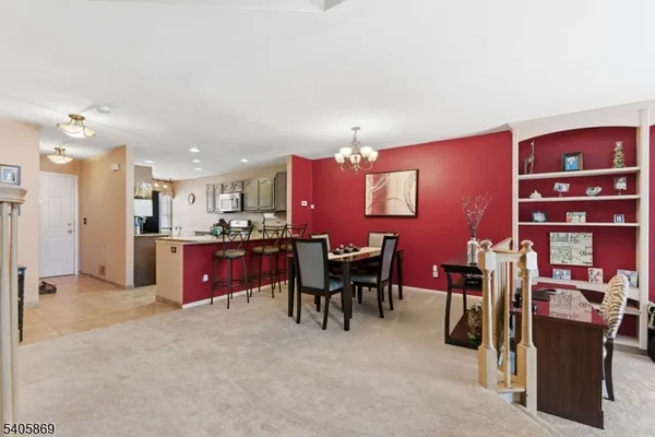 a kitchen with stainless steel appliances kitchen island granite countertop a dining table chairs and a refrigerator