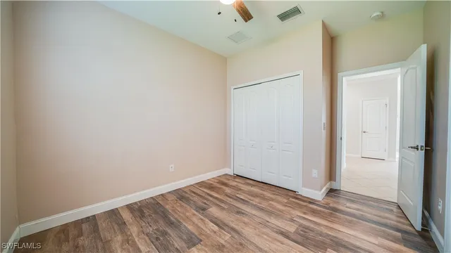 an empty room with wooden floor and a ceiling fan