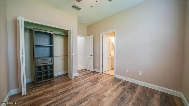 an empty room with wooden floor door and windows